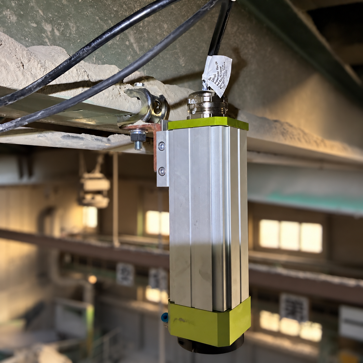 Stellai fixed camera mounted to an industrial beam against a softly blurred recycling-facility background